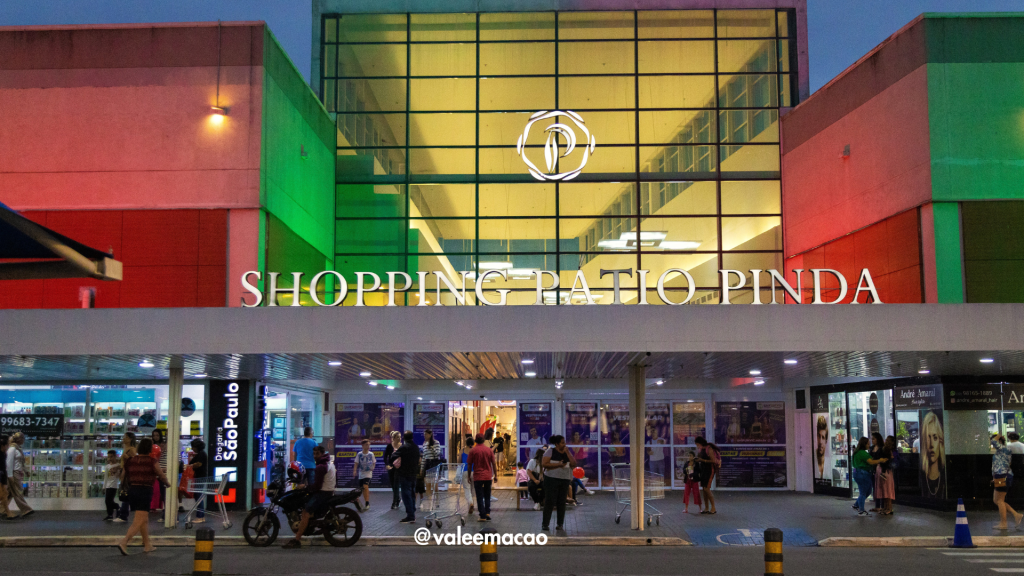Imagem do Shopping Pátio Pinda iluminado e decorado para as festas de fim de ano, com clientes felizes fazendo compras e aproveitando as promoções especiais. O ambiente festivo reflete a alegria das celebrações natalinas, destacando a ampla variedade de lojas e opções de lazer disponíveis